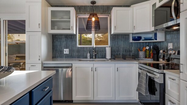 A modern kitchen with white cabinets, a stainless steel dishwasher, and an oven.