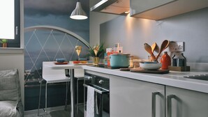 Une cuisine moderne dotée d’une grande fenêtre, d’un plan de travail blanc et d’appareils électroménagers en acier inoxydable.