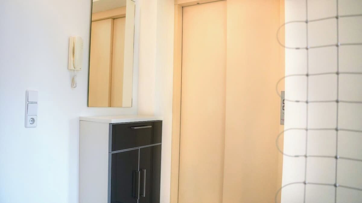 A bathroom with a mirror, a telephone, and a cabinet.