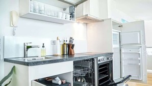 A modern kitchen with a built-in dishwasher, a double oven, and a countertop with a sink. - JH Apartments Ingolstadt | Penthouse Altstadt (Ingolstadt)