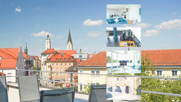 A hotel with red-tiled roofs, a prominent church tower, and a balcony with outdoor seating. - JH Apartments Ingolstadt | Penthouse Altstadt (Ingolstadt)
