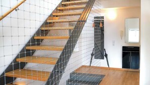 A modern staircase with wooden steps and a metal safety net. - JH Apartments Ingolstadt | Penthouse Altstadt (Ingolstadt)