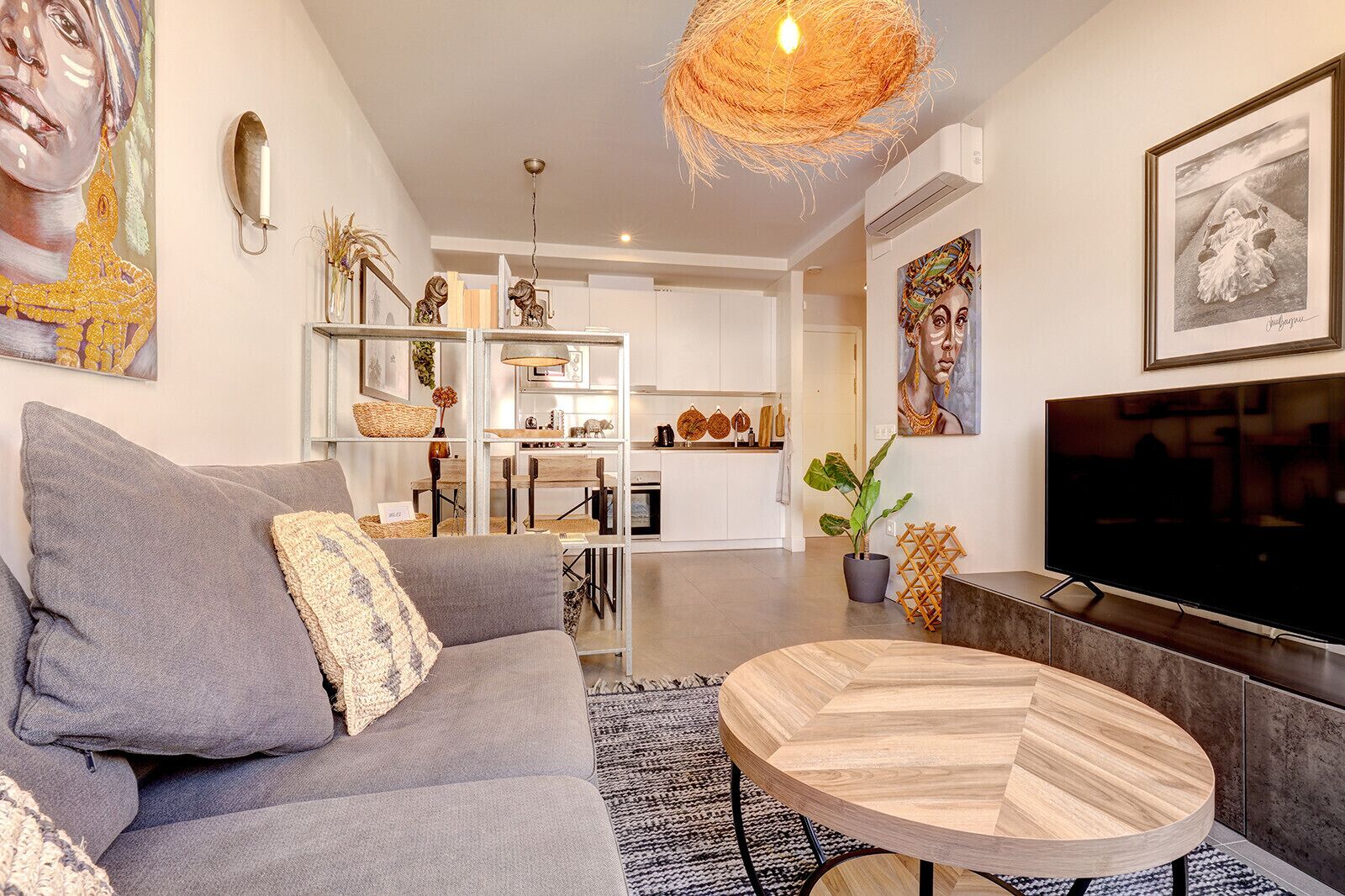 A modern living room with a grey sofa, a round wooden coffee table, and a flat-screen TV.