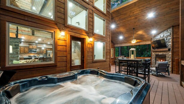 Uma cabana de madeira com banheira de hidromassagem, cozinha e área de estar externa.