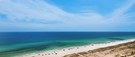An aerial view of a beach with a parking lot and a road.