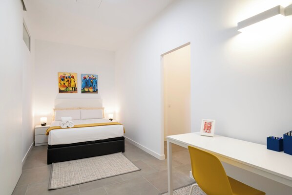 A modern bedroom with a bed, bedside tables, a desk, and a chair. - Dobo Madrid Cochabamba (Madrid)