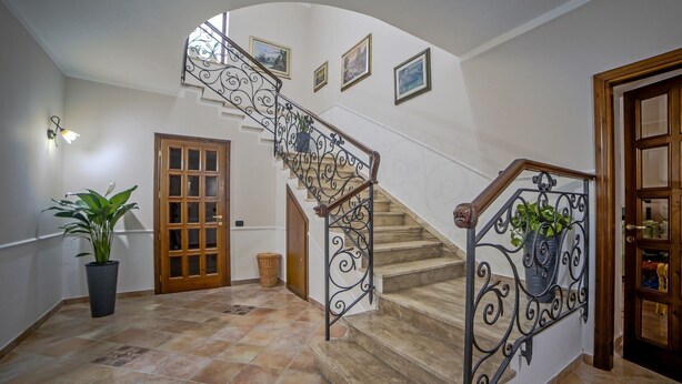 A staircase with ornate metal railings, a potted plant, and a door with a glass panel. - At Ale's House every detail is thought of for you! (Isola del Liri)
