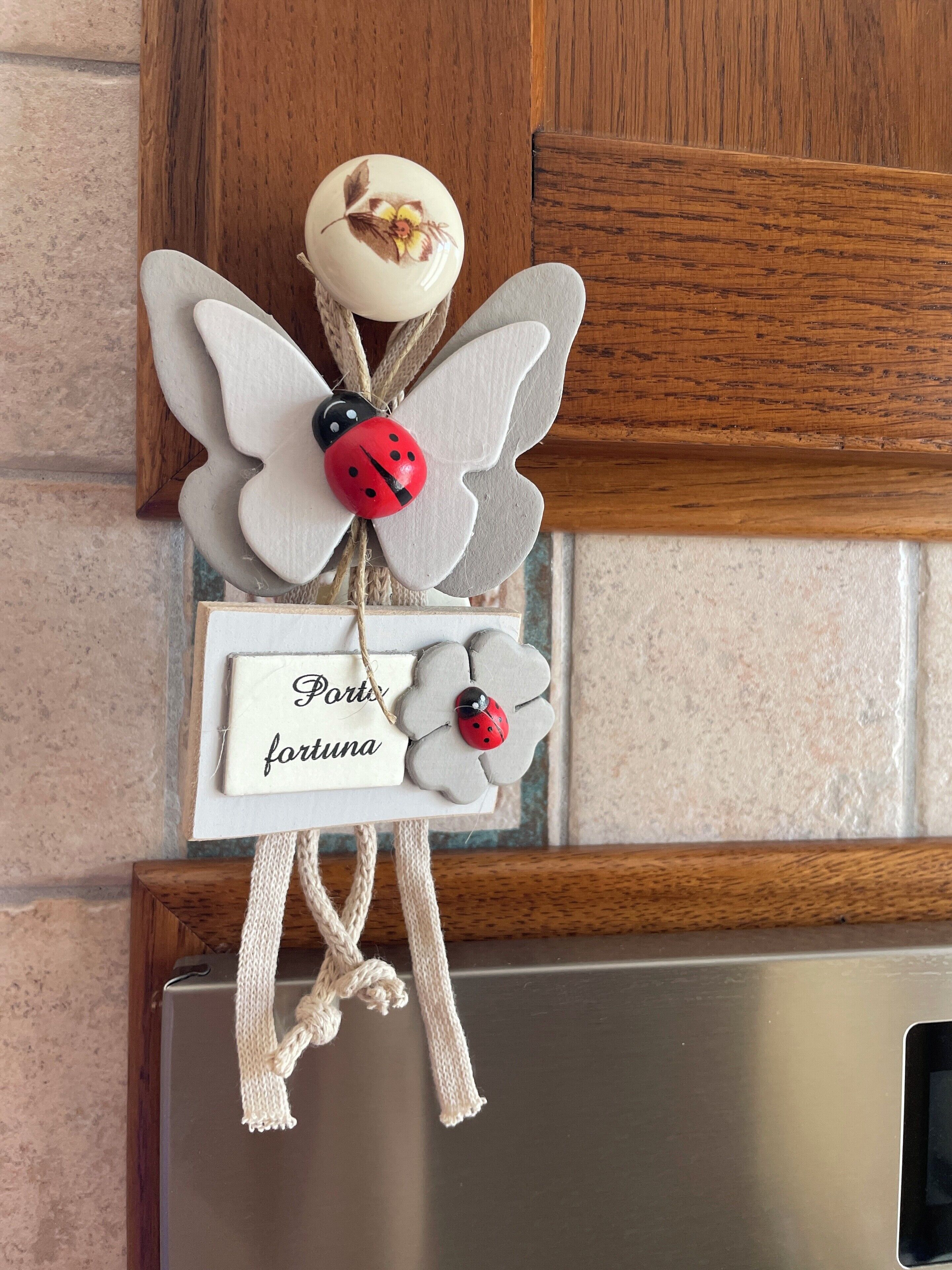 A decorative item with a ladybug and a sign that reads 'Porto fortuna' hanging on a wooden surface.