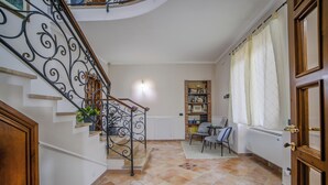 A spacious hallway with a staircase, a seating area with a table and chairs, and a bookshelf filled with books. - At Ale's House every detail is thought of for you! (Isola del Liri)