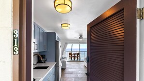 Eine moderne Küche mit blauen Schränken, einem Edelstahlkühlschrank und einem Essbereich mit Meerblick.
