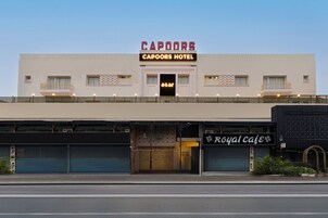 Un hotel con un cartel que dice "Capoors Hotel" y un escaparate con la leyenda "Royal Cafe".