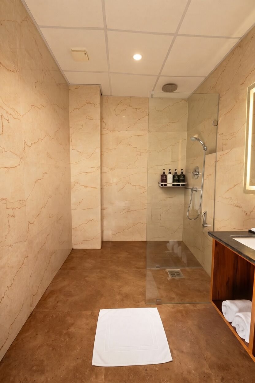Une salle de bain moderne avec une douche à parois de verre, des murs en marbre et un meuble-lavabo en bois.