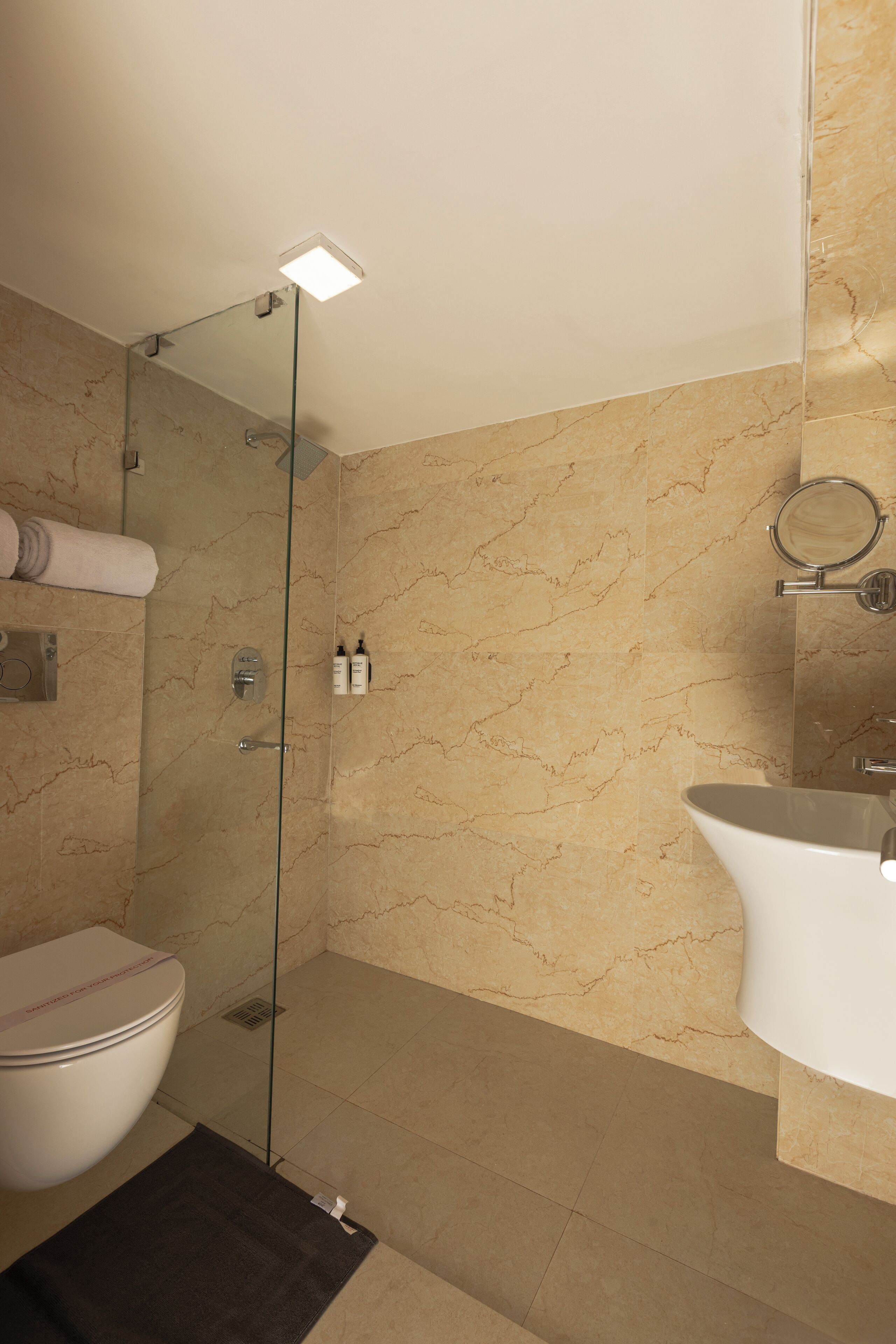 Une salle de bain avec une douche à parois de verre, des toilettes, un lavabo et un miroir.