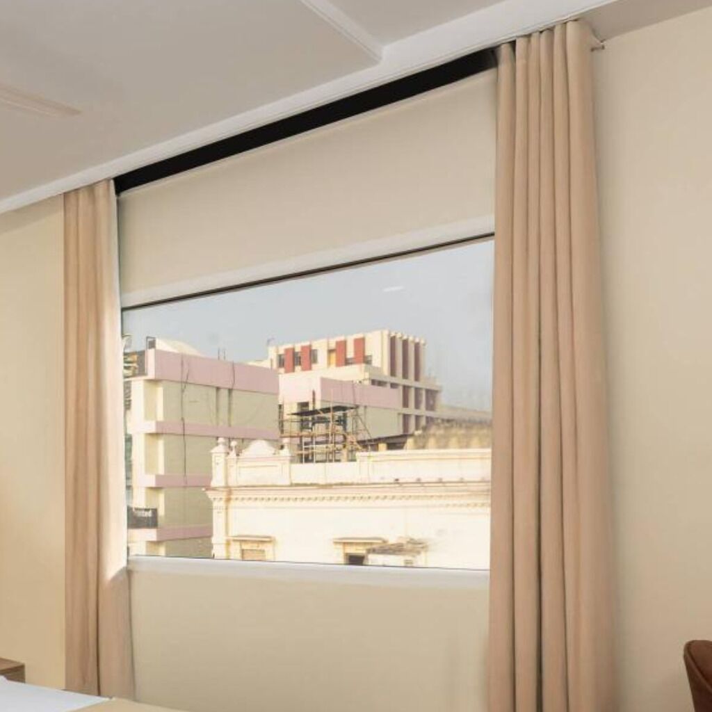 Una habitación de hotel con un ventanal grande, una cama y cortinas.
