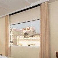 Una habitación de hotel con un ventanal grande, una cama y cortinas.