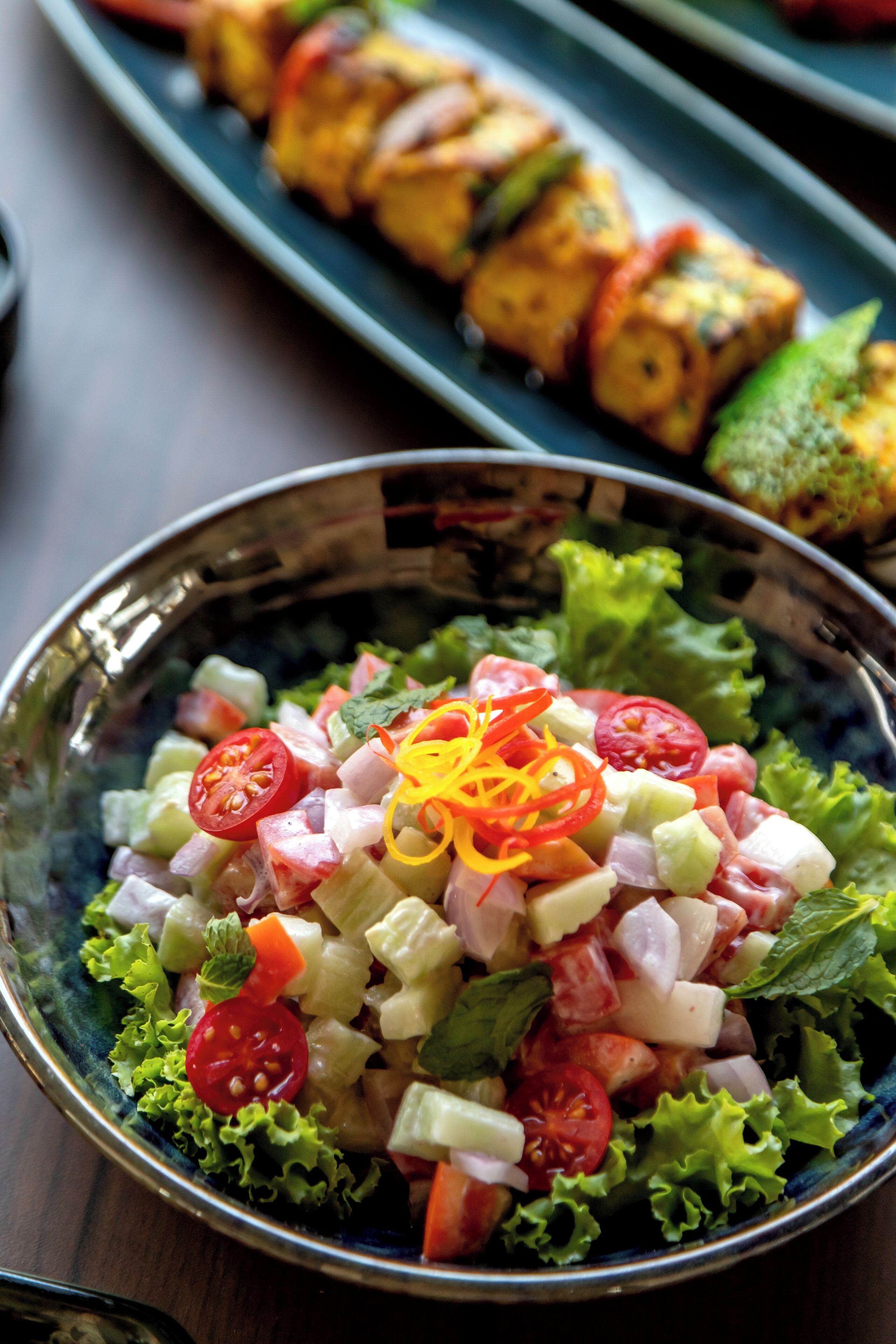 A bowl of salad with various vegetables and a decorative garnish.