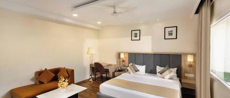 Una habitación de hotel con una cama grande, un sofá, un escritorio y una silla.