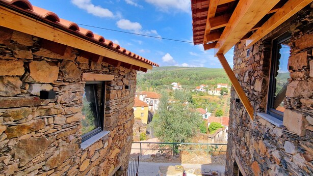 A stone building with a balcony overlooking a village.
