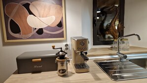 A kitchen counter with a coffee machine, a bread box, and a jar of coffee.