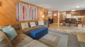 A living room with a sofa, blue ottoman, and a wall with wooden panels and artwork. - 3 Bedroom Kirkwood Condo Base Camp 3 Condo (Kirkwood)