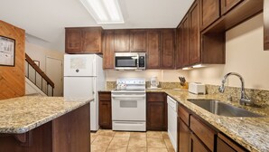 A kitchen with wooden cabinets, a white refrigerator, a microwave, a stove, a sink, and granite countertops. - 3 Bedroom Kirkwood Condo Base Camp 3 Condo (Kirkwood)