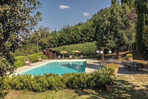 Una piscina circondata dal verde, con lettini e ombrelloni.