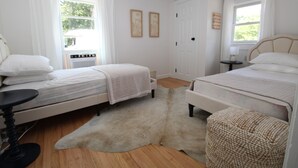 Quarto com duas camas, uma mesinha, uma cadeira e um tapete de pele.