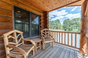 Una baita di legno con veranda, due sedie di legno e un'ampia finestra.