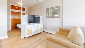 Un salon avec un meuble de rangement blanc pour l’équipement audiovisuel, un canapé beige et une porte en bois.