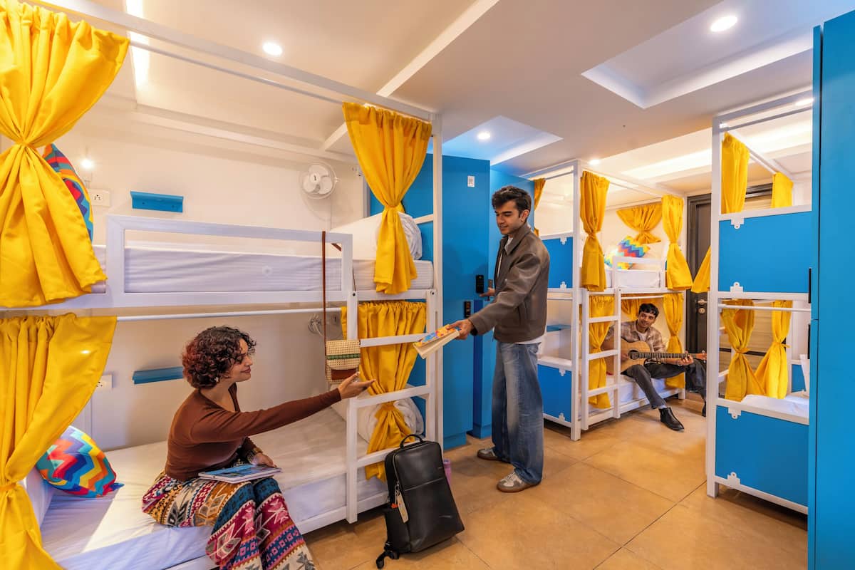 A dormitory room with bunk beds, yellow curtains, and a fan.