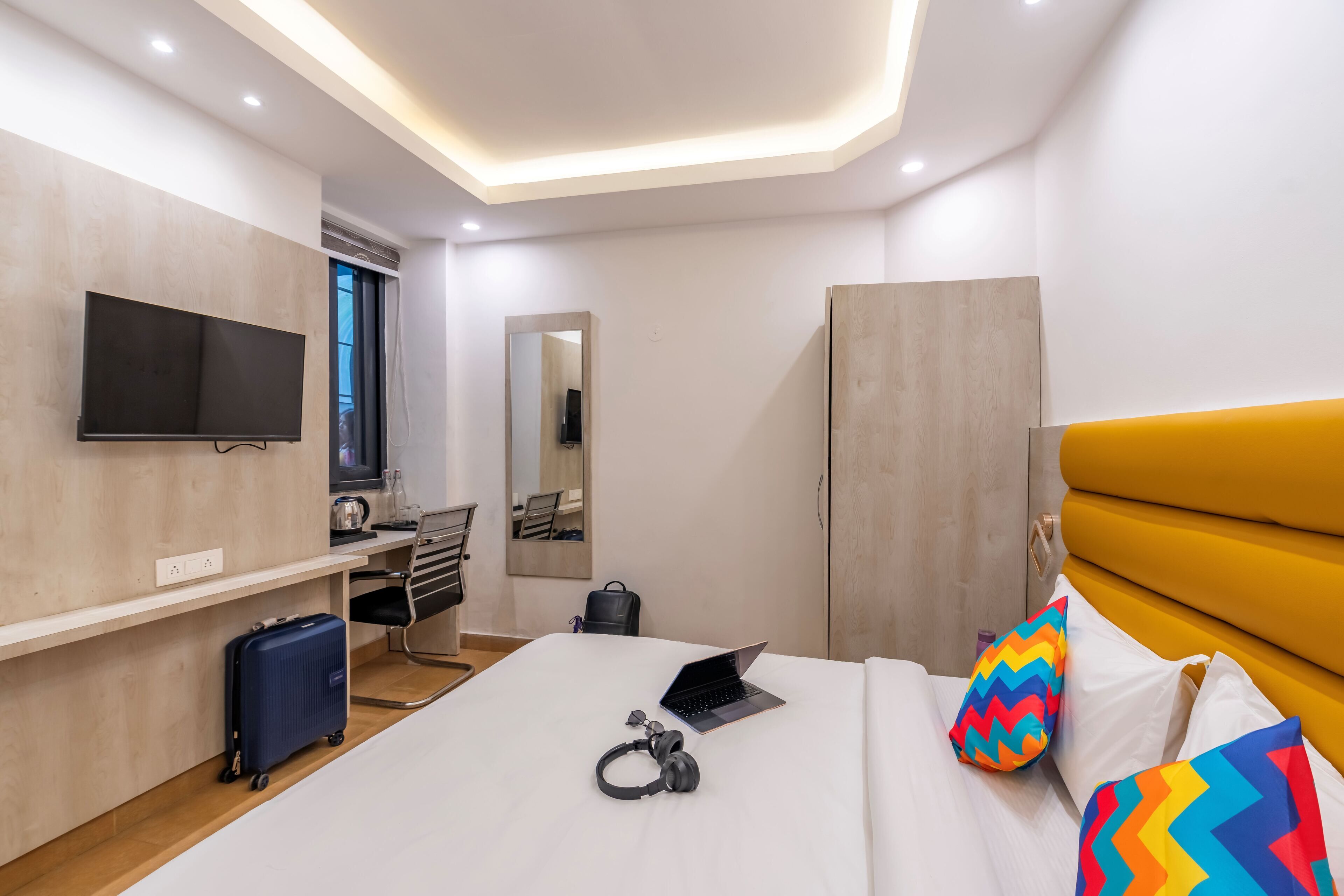 Una habitación de hotel moderna con una cama, un escritorio, un televisor y un armario.