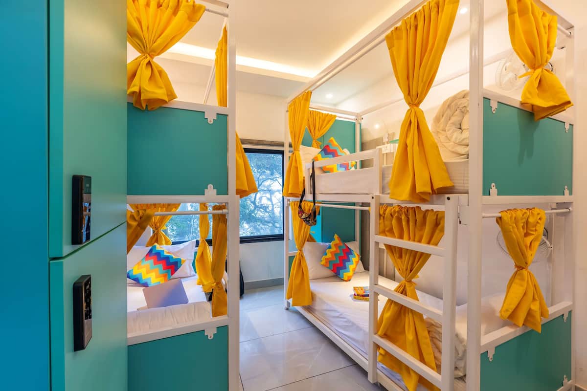 A room with bunk beds, teal walls, and yellow curtains tied at the ends.