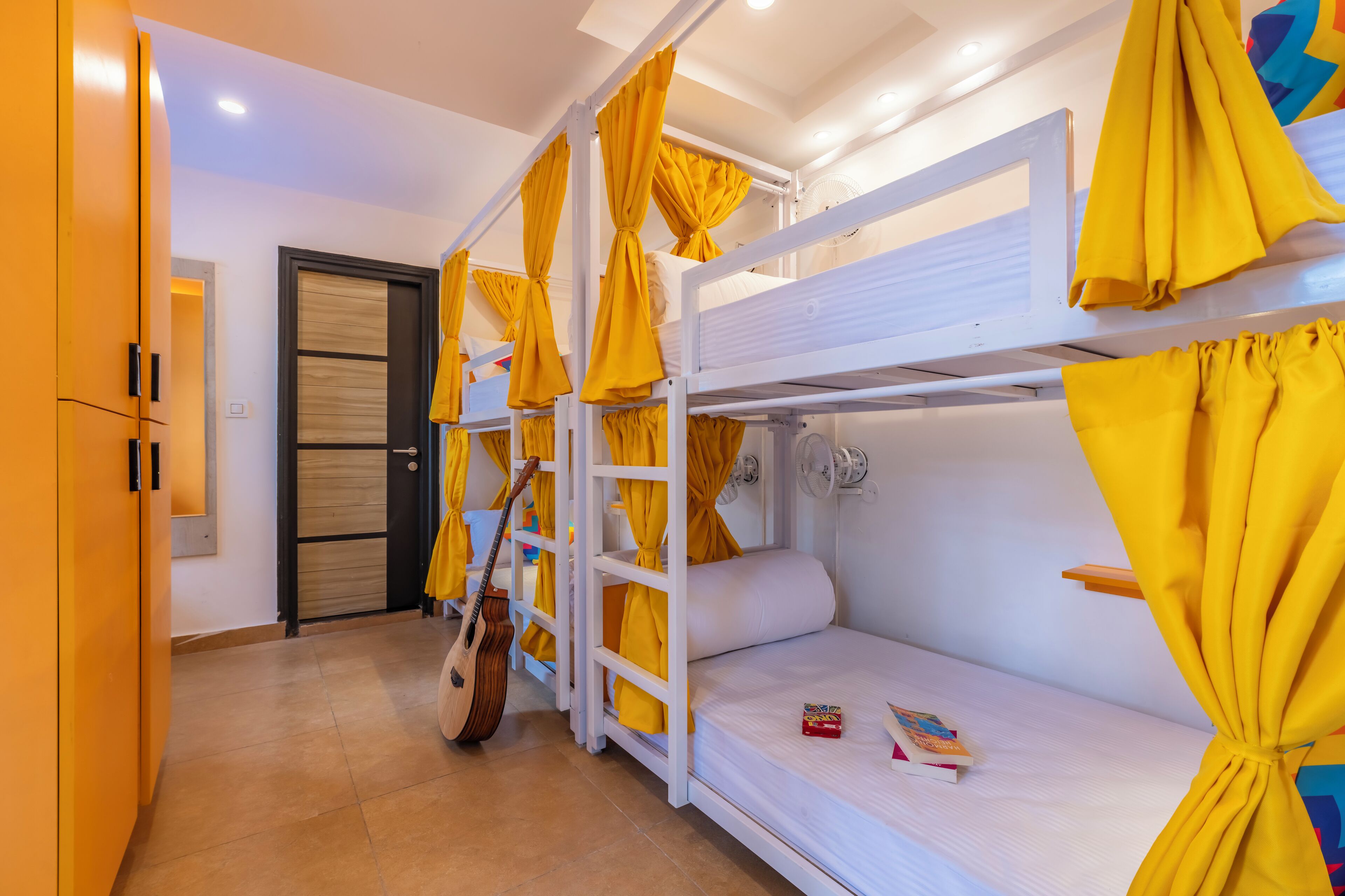 A bunk bed room with yellow curtains, a guitar, and a door.