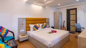 A modern hotel room with a large bed, a desk, a chair, a guitar, and a wardrobe. - goSTOPS Mussoorie Clock Tower (Mussoorie)