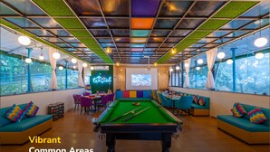 A vibrant common area with a pool table, seating, and large windows. - goSTOPS Mussoorie Clock Tower (Mussoorie)