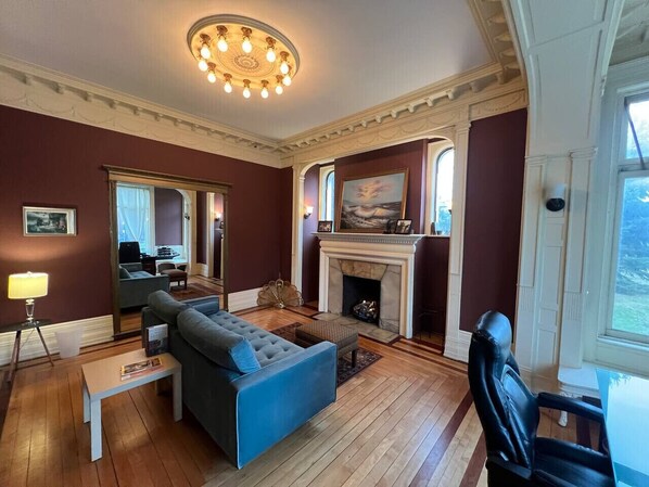 Ein Wohnzimmer mit blauem Sofa, Kamin und einer Chandelüster.