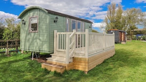 A small, single-story cabin with a porch and steps, surrounded by a grassy yard and trees. - The Dragonfly (Driffield)