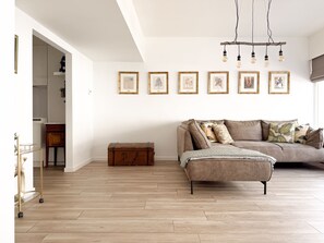 Un salon moderne avec un canapé, une commode en bois et un mur décoratif où sont accrochées des photos encadrées.