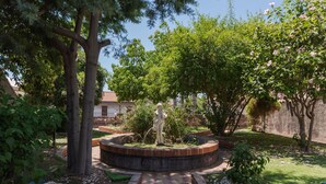 Ein Garten mit einer Statue, Bäumen und einem Pflasterweg.