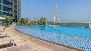 A swimming pool with a view of a tall bridge and a high-rise building in the background. - Elegant 1 Bed | Canal Views | Close to Ain Dubai I 5242 Tower 2 (Dubai Marina)