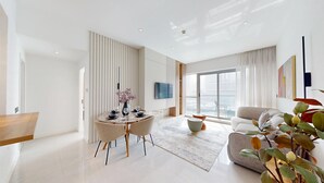 A modern living room with a dining area, large windows, and a flat-screen TV.