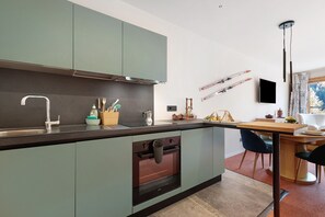 A modern kitchen with a built-in oven, a sink, and a dining area with a table and chairs.