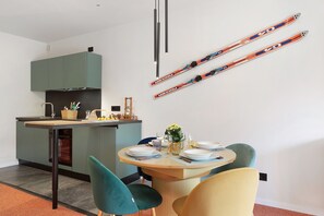 A modern kitchen with a dining area, a table set for two, and skis hanging on the wall.