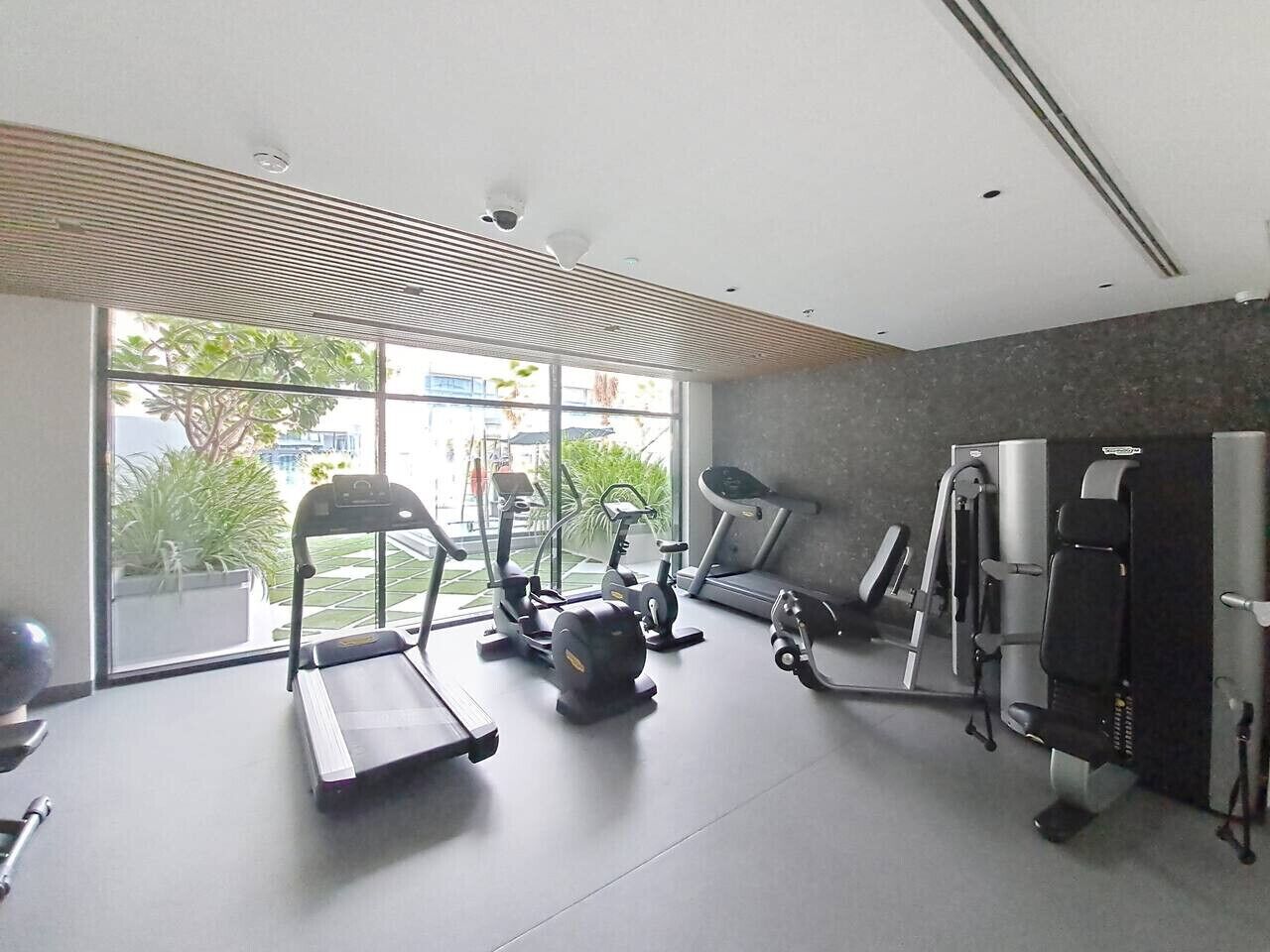 Une salle de sport équipée de tapis de course, de vélos elliptiques et d’un banc de musculation.