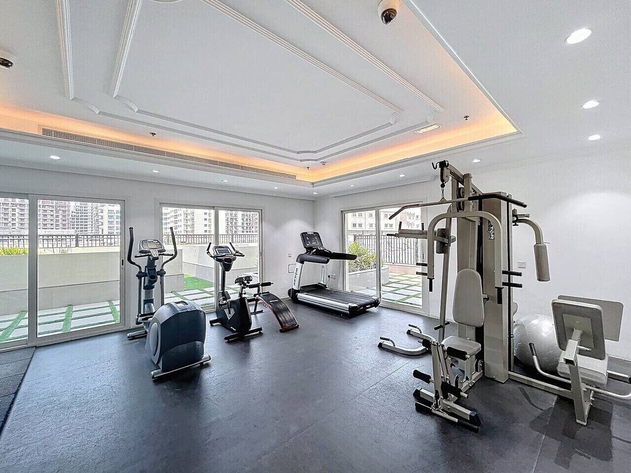 Une salle de sport moderne dotée de divers équipements d’exercice, de grandes fenêtres et d’un aménagement propre et spacieux.