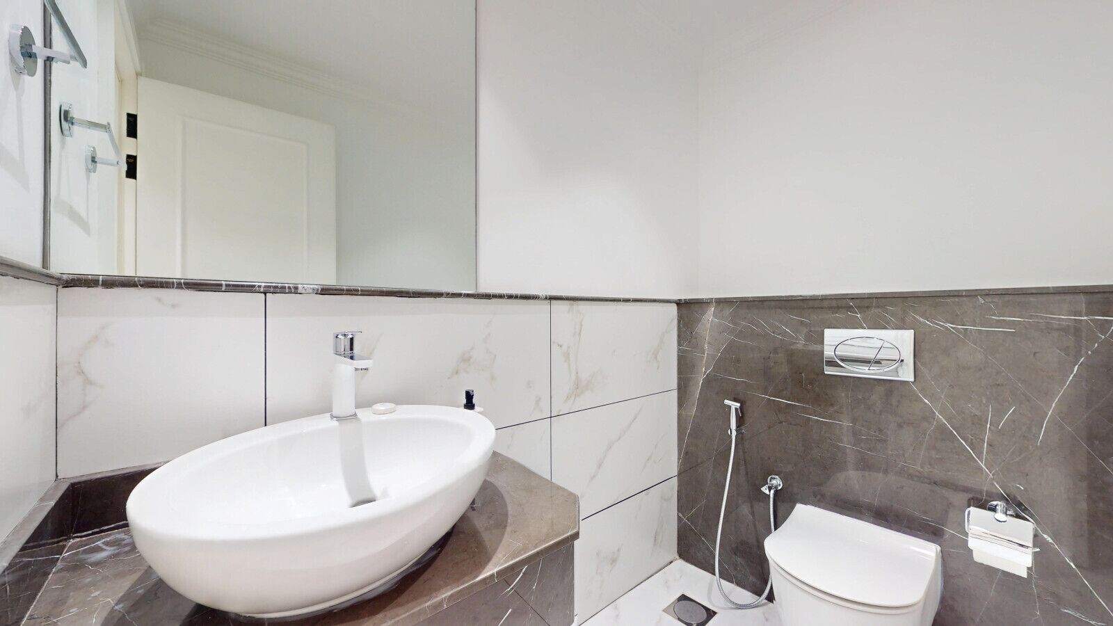 Et badeværelse med en stor, hvid vask, toilet og bruseområde.