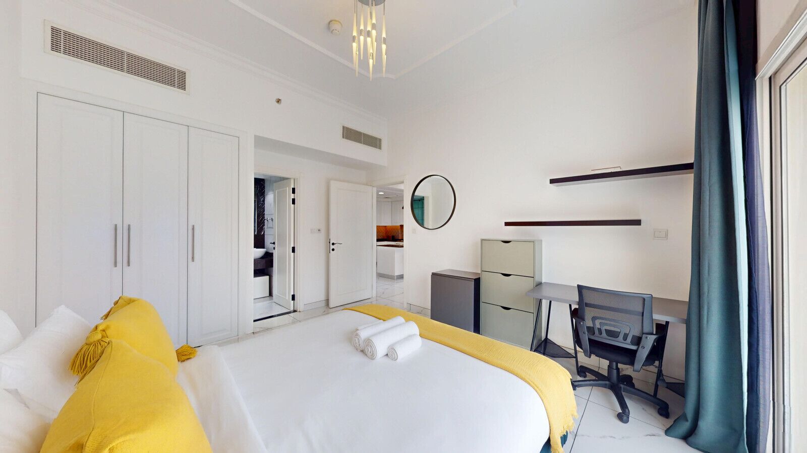 Ein Hotelzimmer mit einem großen Bett, einem Schreibtisch, einem Sessel, einem Spiegel und einem Kleiderschrank.