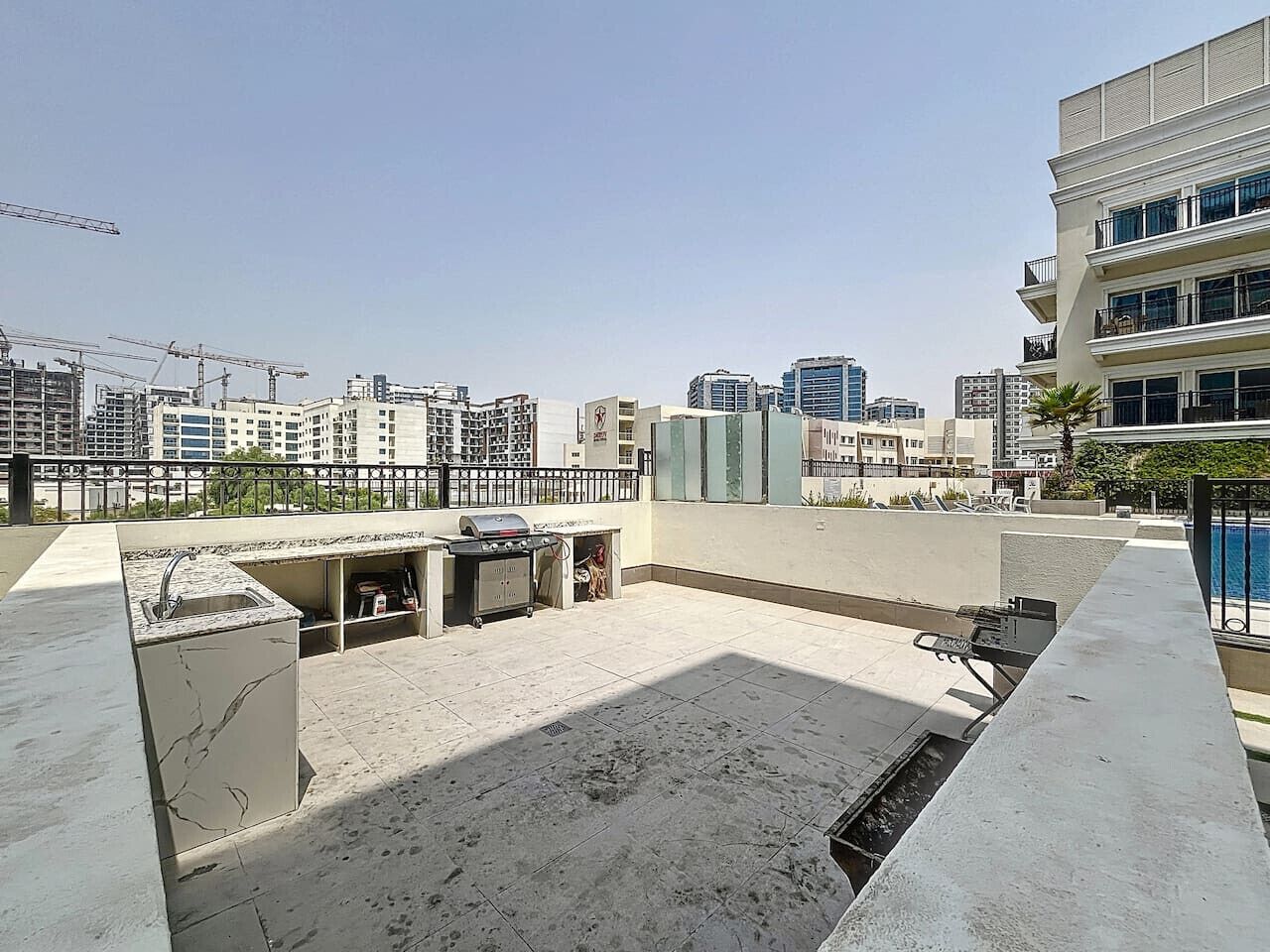 Une terrasse sur le toit, dotée d’un barbecue et d’un évier intégrés, et entourée d’immeubles.
