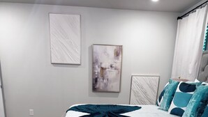 A bedroom with a large bed, a grey headboard, and a blue and white patterned rug. - New construction 3-bedroom house in beautiful Midland with 2 car garage access. (Midland)