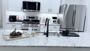 A modern kitchen with white cabinets, stainless steel appliances, and a granite countertop. - New construction 3-bedroom house in beautiful Midland with 2 car garage access. (Midland)